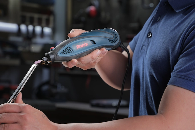 A rotary tool is being used to sharpen a chisel