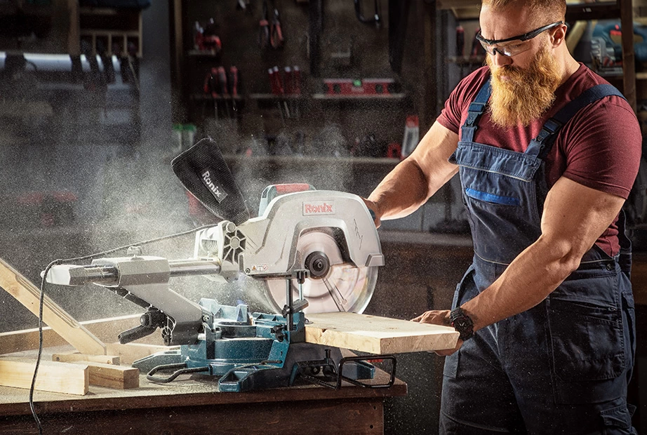 A man using Ronix miter saw to cut through wood